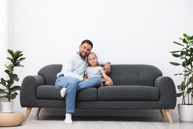 Photo of Father and daughter spending time together on sofa at home