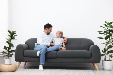 Photo of Father and daughter spending time together on sofa at home