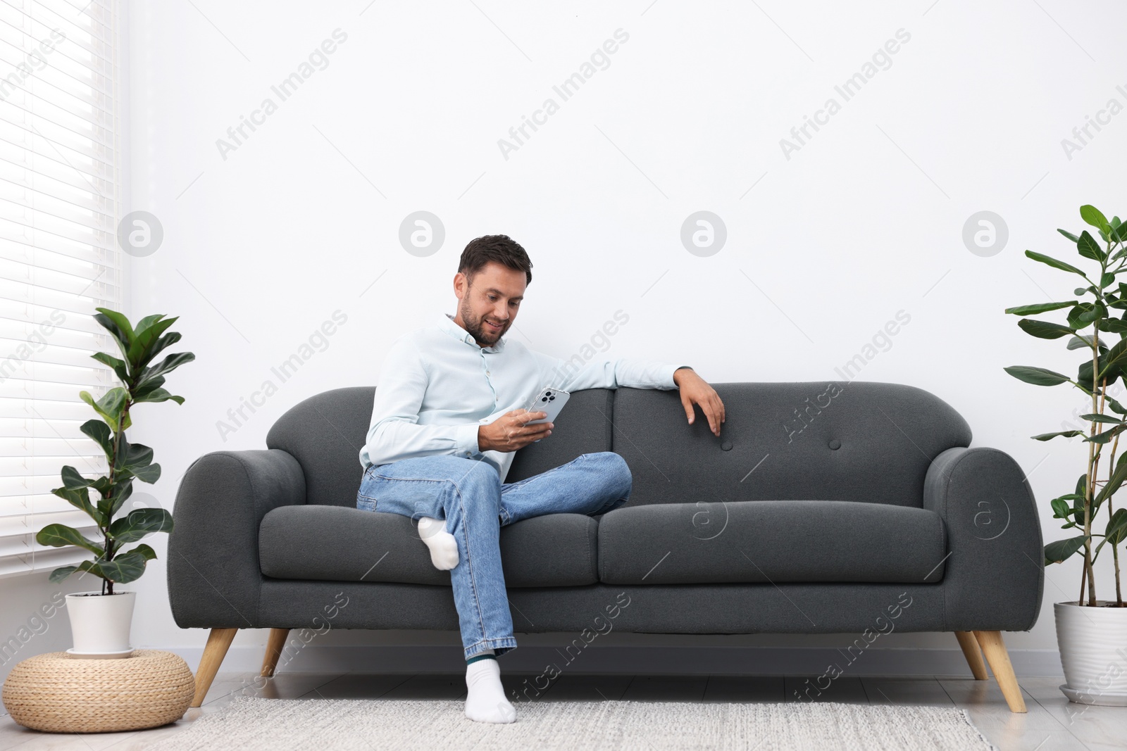 Photo of Man with smartphone on sofa at home