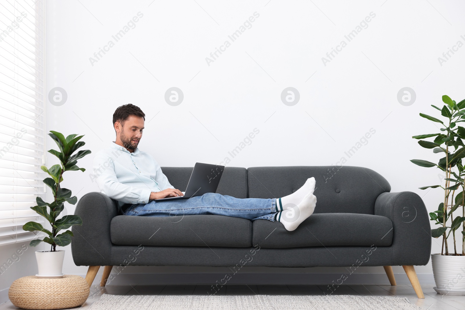 Photo of Man with laptop on sofa at home. Space for text