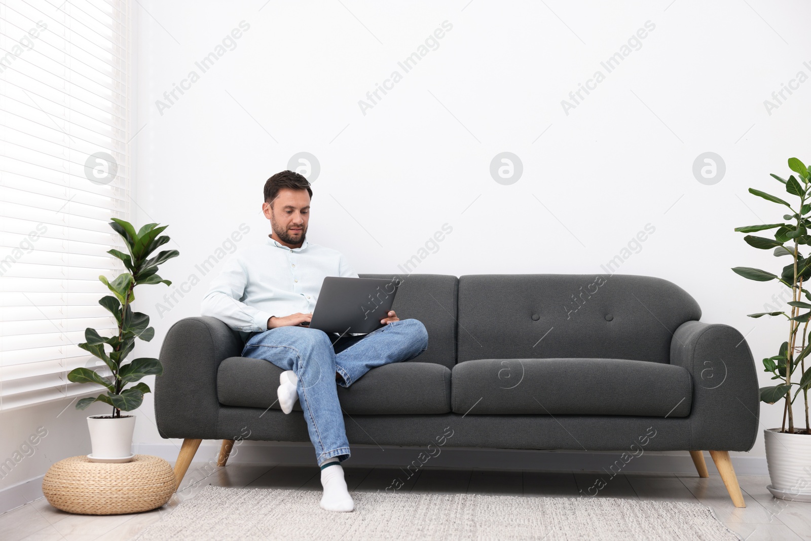 Photo of Man with laptop on sofa at home. Space for text