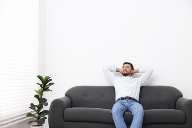 Photo of Happy man resting on sofa at home. Space for text