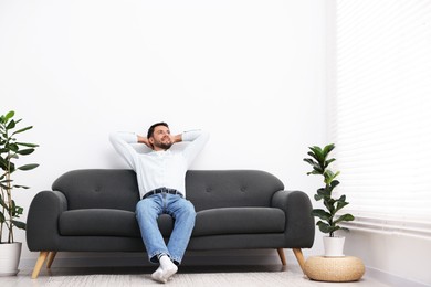 Photo of Happy man resting on sofa at home. Space for text