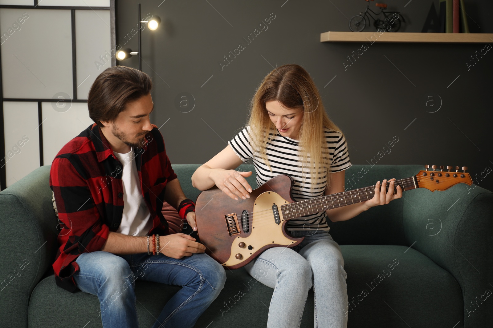 Photo of Tutor teaching woman to play guitar at home