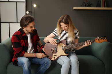 Photo of Tutor teaching woman to play guitar at home