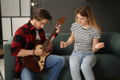Photo of Tutor teaching woman to play guitar at home