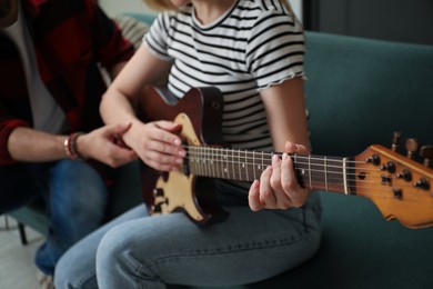 Photo of Tutor teaching woman to play guitar at home, closeup