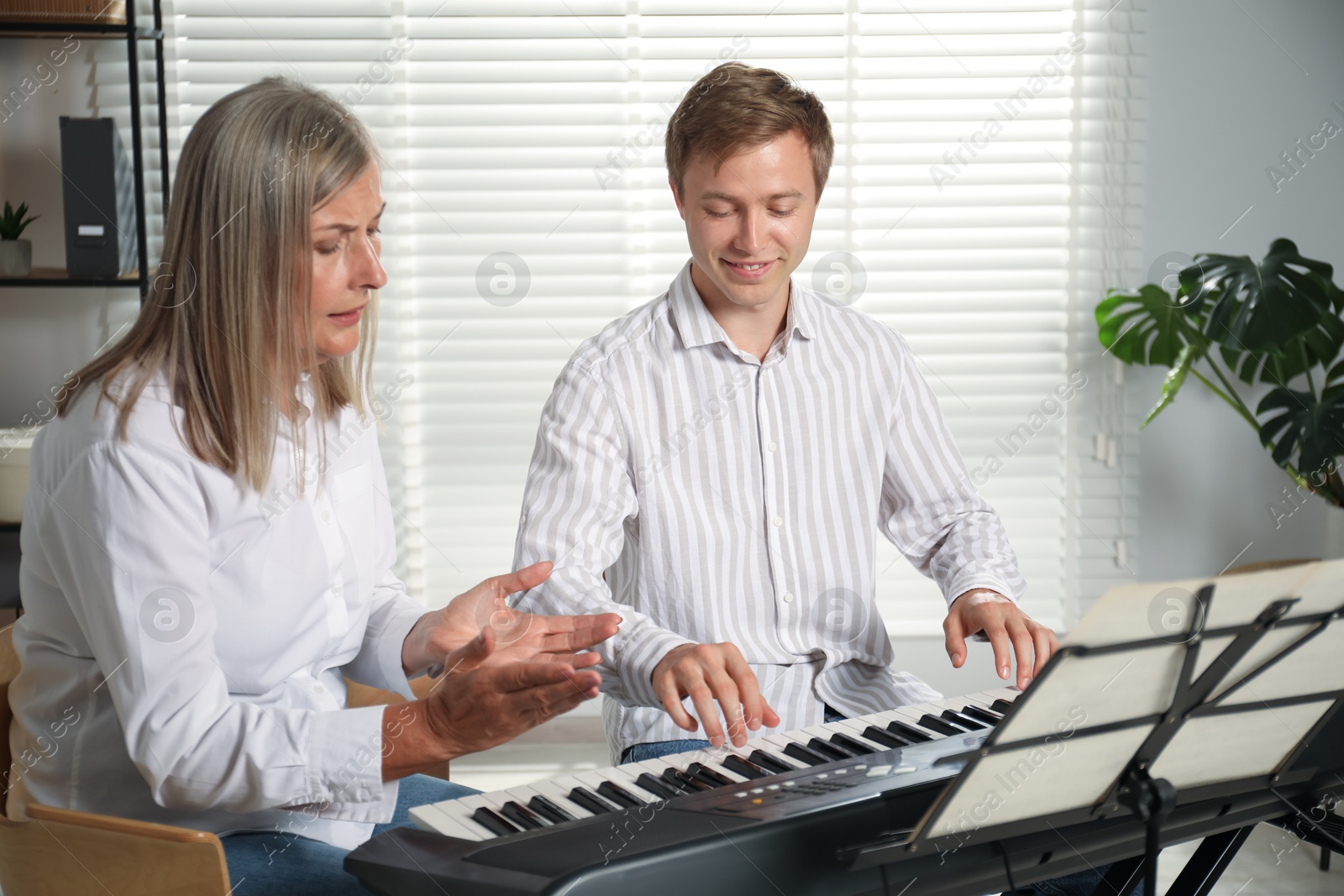 Photo of Tutor teaching man to play piano indoors