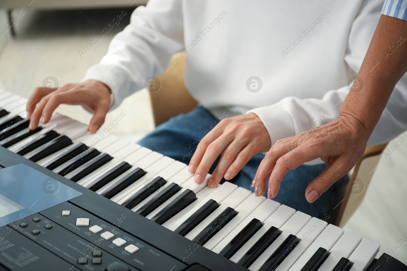 Photo of Tutor teaching man to play piano indoors, closeup