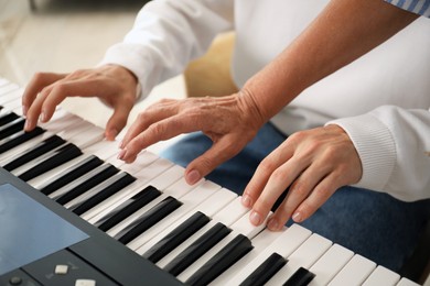 Photo of Tutor teaching man to play piano indoors, closeup
