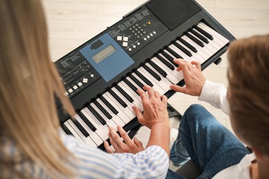 Photo of Tutor teaching man to play piano indoors, closeup