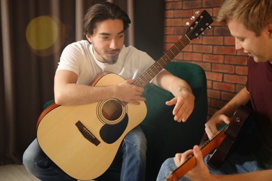 Photo of Tutor teaching man to play guitar indoors