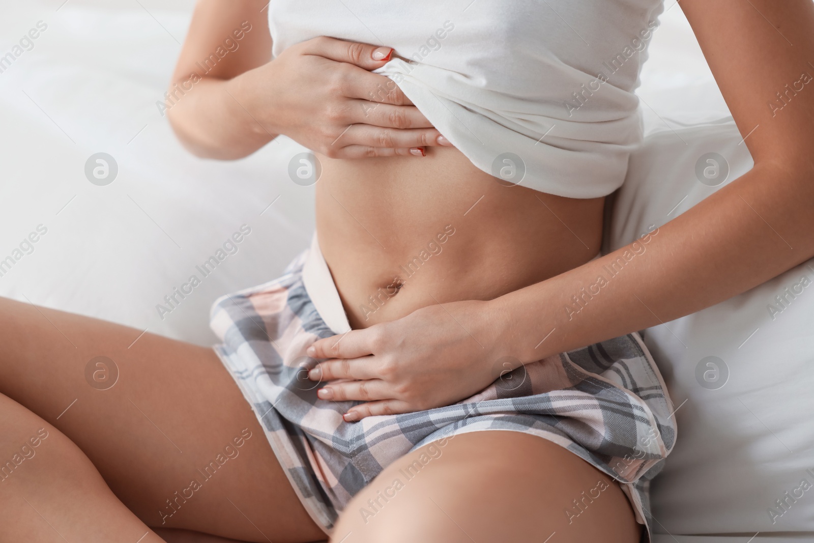 Photo of Young woman with flat belly on bed at home, closeup