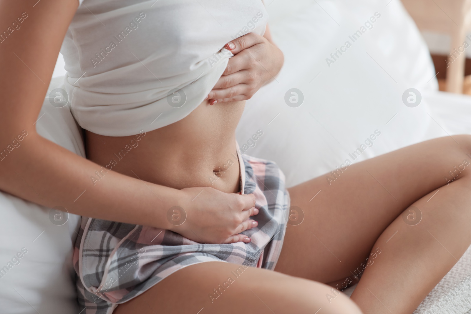 Photo of Young woman with flat belly on bed at home, closeup