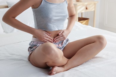 Photo of Young woman with flat belly on bed at home, closeup