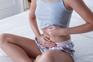 Photo of Young woman with flat belly on bed at home, closeup