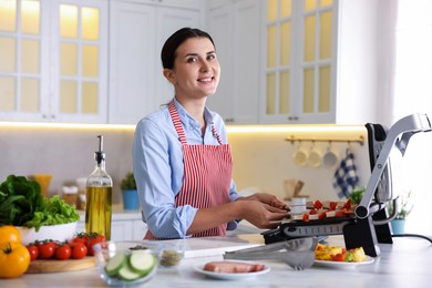Photo of Woman cooking skewers with meat and vegetables on electric grill at home