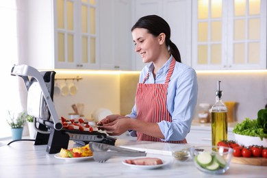 Photo of Woman cooking skewers with meat and vegetables on electric grill at home