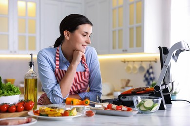 Photo of Woman cooking vegetables and meat on electric grill in kitchen
