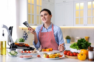 Photo of Woman cooking vegetables and meat on electric grill in kitchen