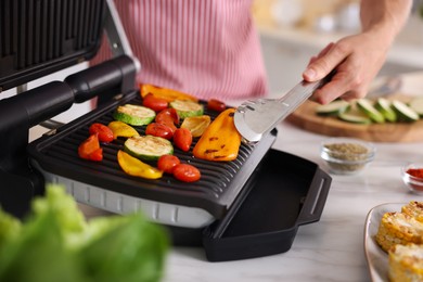 Photo of Man cooking vegetables on electric grill in kitchen, closeup