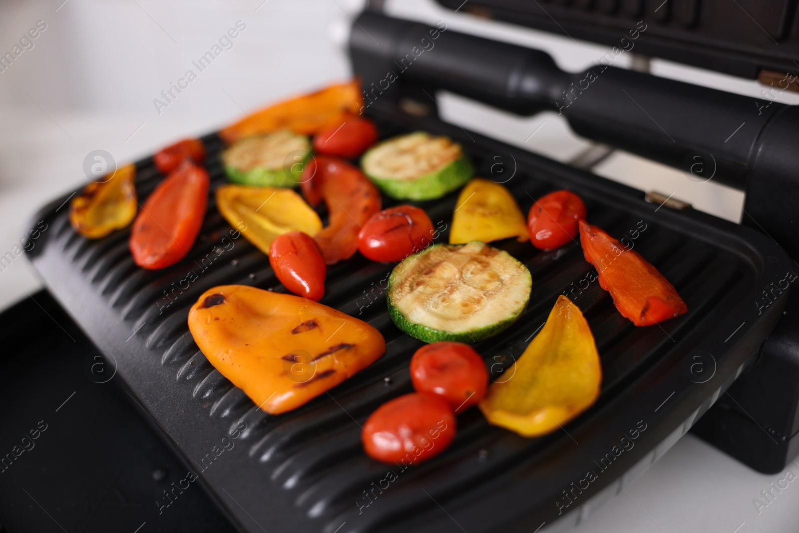 Photo of Electric grill with different vegetables on white table, closeup