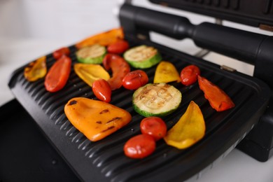 Photo of Electric grill with different vegetables on white table, closeup