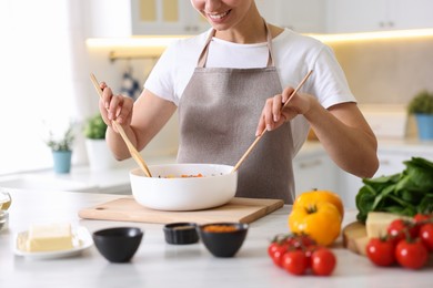 Photo of Smiling woman cooking at table in kitchen, closeup