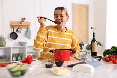 Photo of Smiling woman cooking at table in kitchen