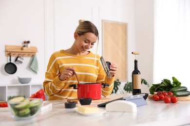 Photo of Smiling woman cooking at table in kitchen