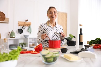 Photo of Smiling woman cooking at table in kitchen