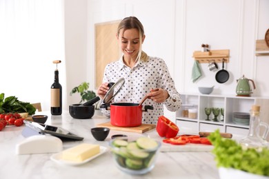 Photo of Smiling woman cooking at table in kitchen
