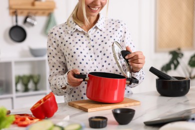 Photo of Smiling woman with pot cooking at table in kitchen, closeup