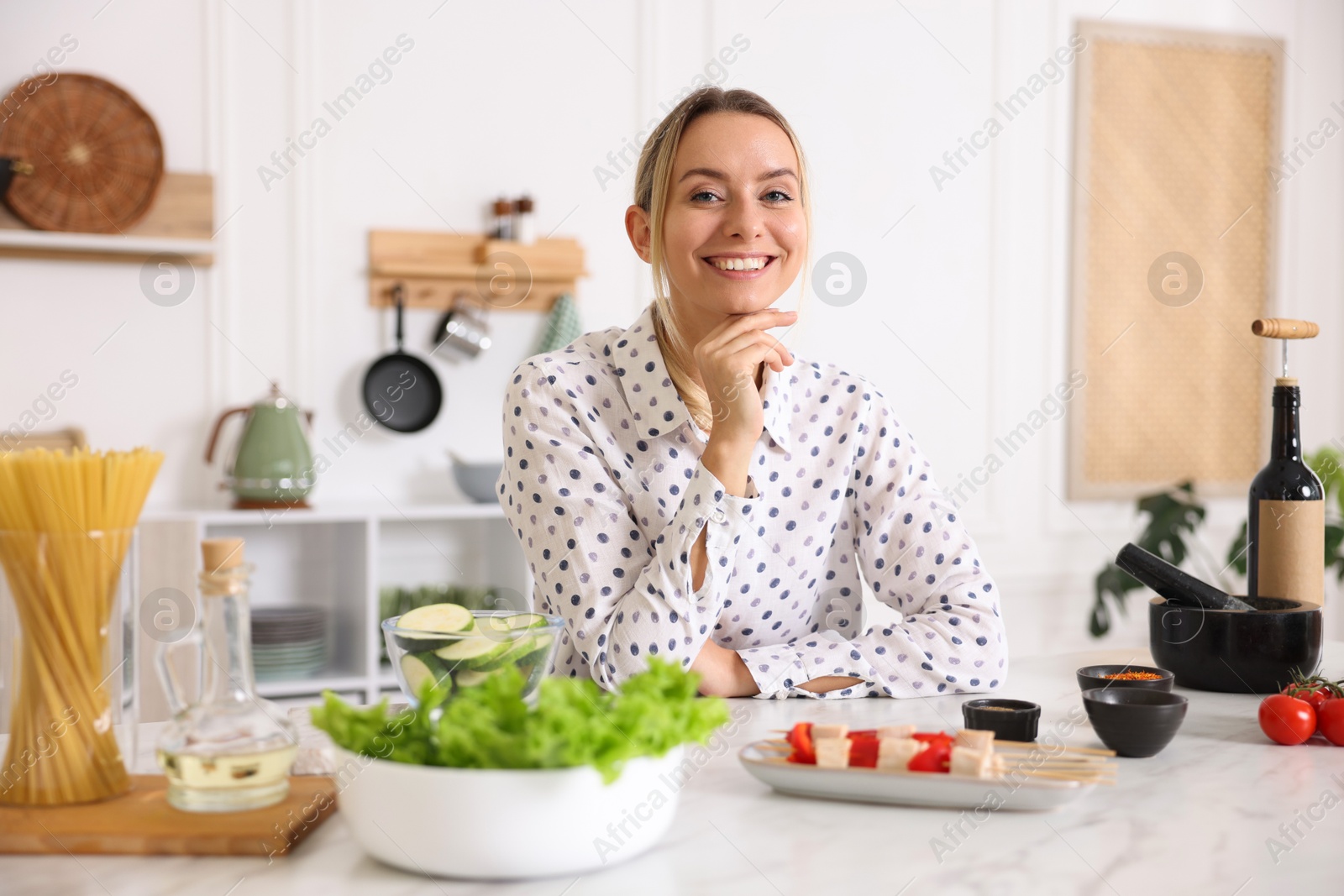Photo of Portrait of smiling woman cooking at table in kitchen