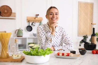 Photo of Portrait of smiling woman cooking at table in kitchen