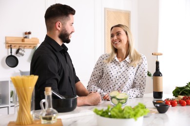 Photo of Happy couple cooking together at table in kitchen