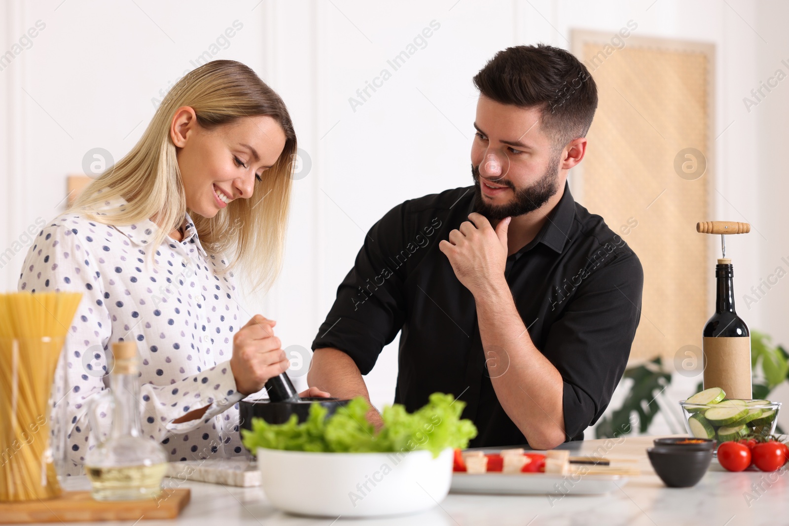 Photo of Happy couple cooking together at table in kitchen