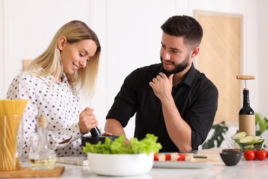 Photo of Happy couple cooking together at table in kitchen