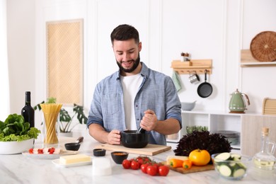 Photo of Smiling man cooking at table in kitchen