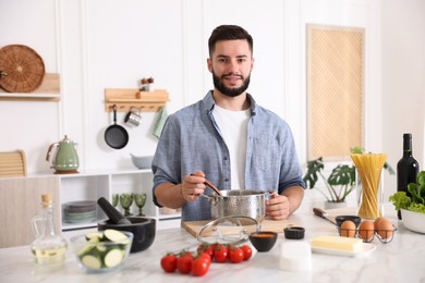 Photo of Smiling man cooking at table in kitchen