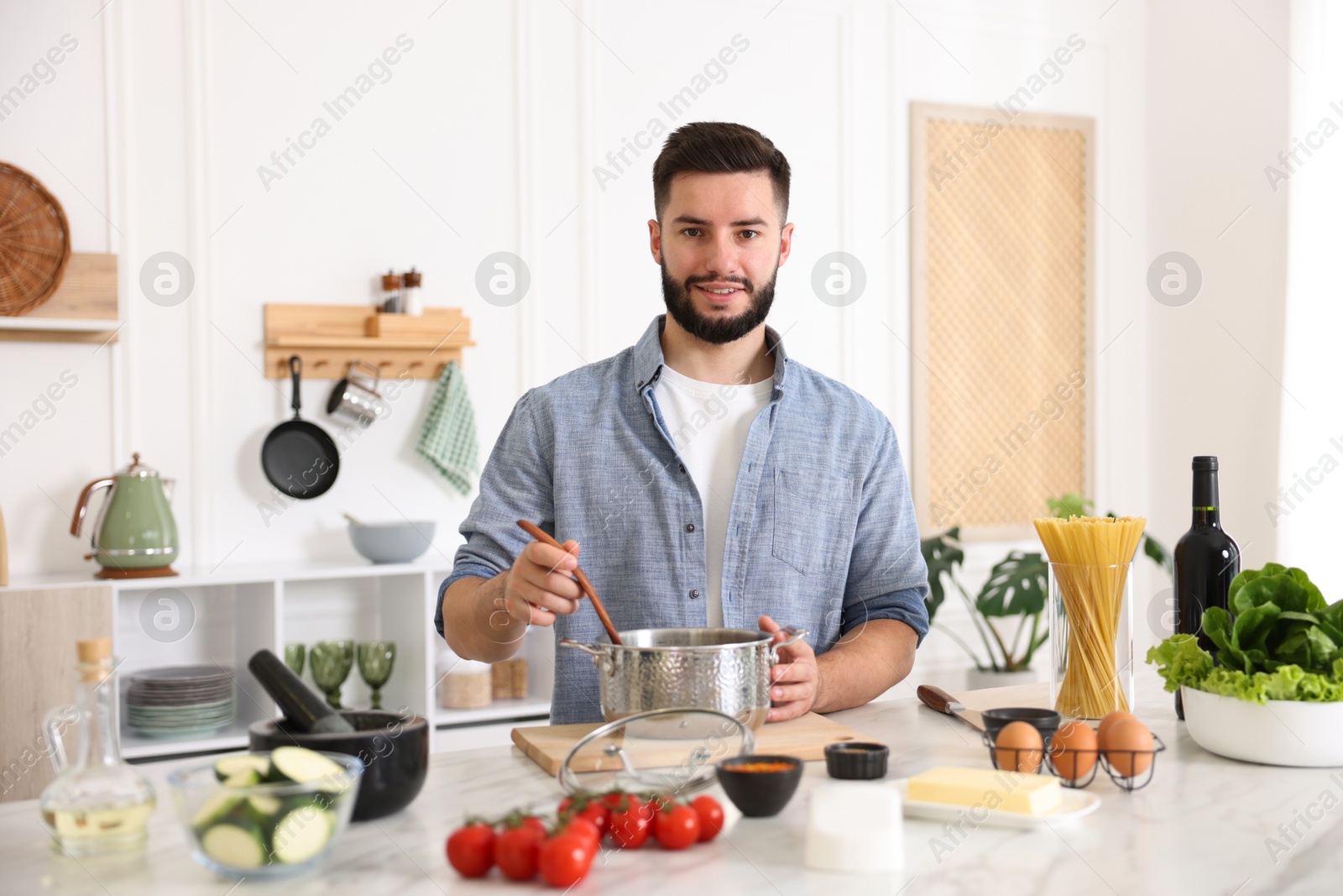 Photo of Smiling man cooking at table in kitchen