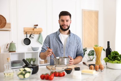Photo of Smiling man cooking at table in kitchen
