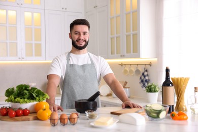 Photo of Smiling man cooking at table in kitchen
