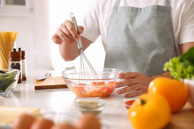 Photo of Man with whisk cooking at table indoors, closeup