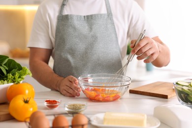 Photo of Man with whisk cooking at table indoors, closeup