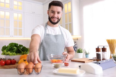 Photo of Smiling man cooking at table in kitchen