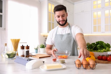 Photo of Smiling man cooking at table in kitchen