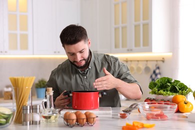 Photo of Young man cooking at table in kitchen