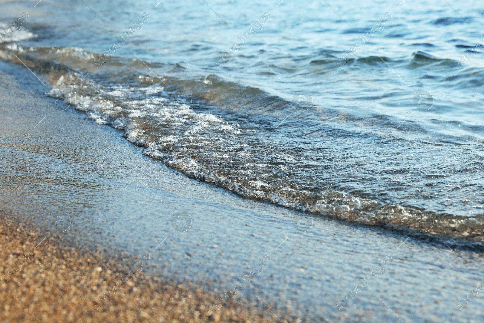Photo of Beautiful wavy sea and sandy beach, closeup