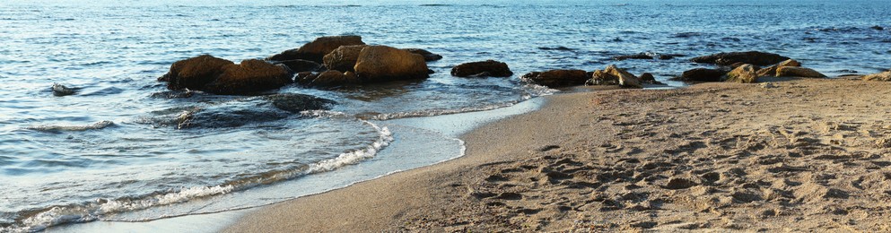 Photo of Beautiful wavy sea, stones and sandy beach